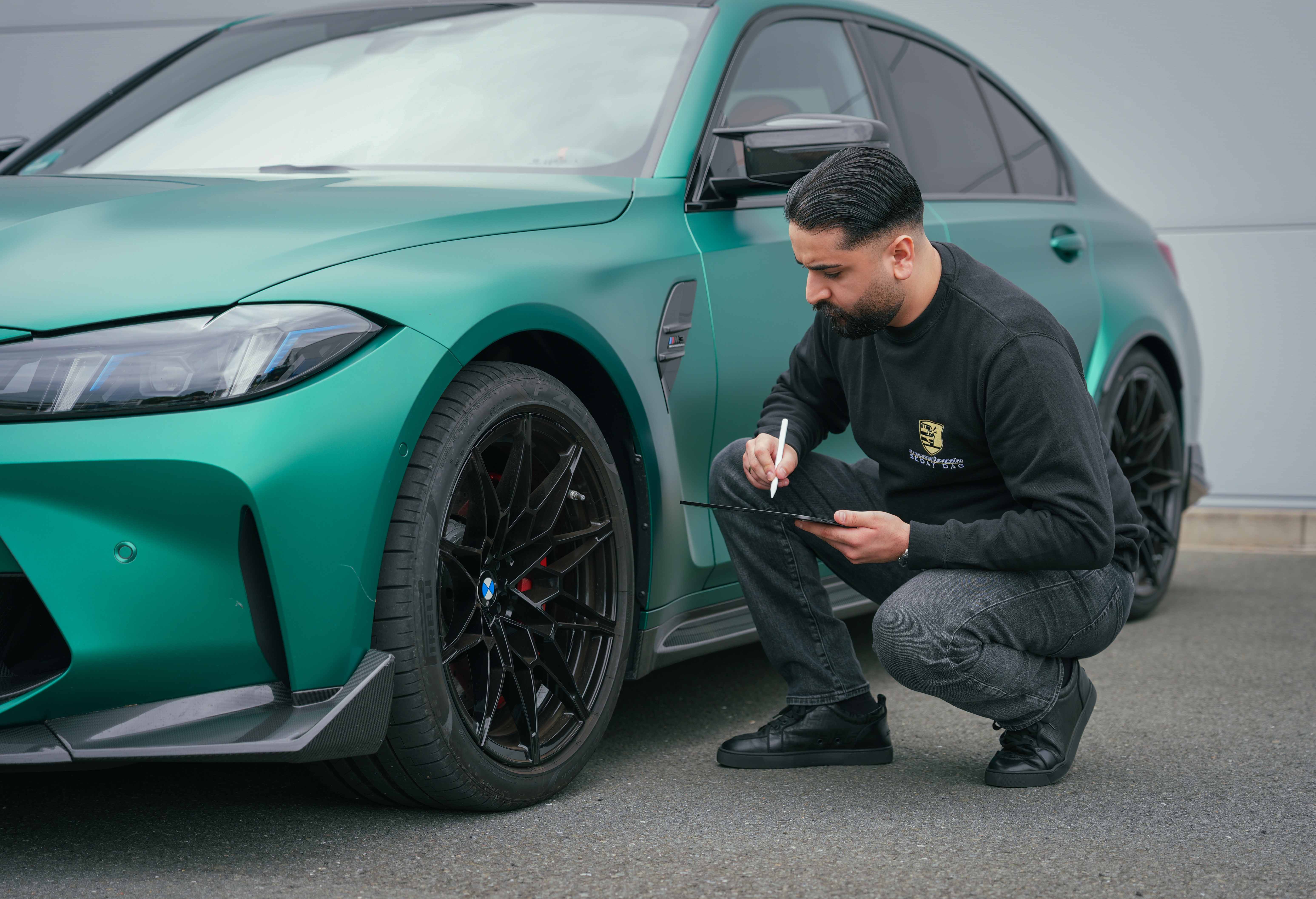 KFZ-Sachverständiger Sedat Dag bei der Begutachtung eines Fahrzeugs mit Tablet